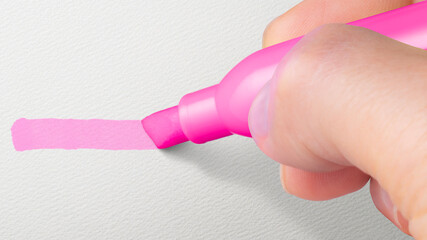 蛍光ペンでピンク色のラインを引いている手