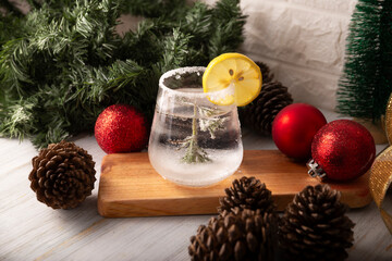 Snow Globe Cocktail. Christmas drink, creative festive beverage in drink glass decorated with rosemary sprig like a christmas pine tree and citrus slice.