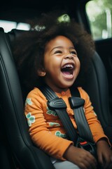Little dark-skinned girl with curly hair laughs in a child car seat, safety concept