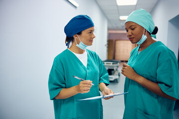 Female doctors going through paperwork while preparing for surgery in hospital.