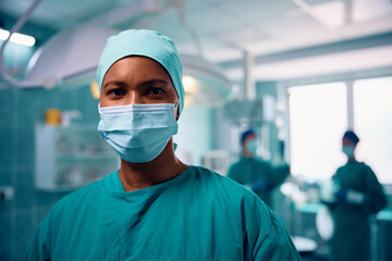 Black female surgeon in operating room looking at camera.