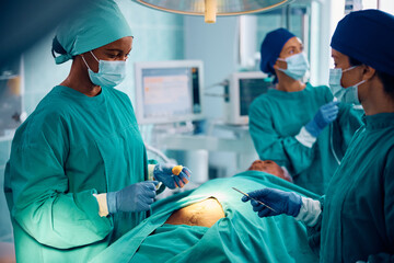 Black surgeon and her medical team performing surgery in hospital.