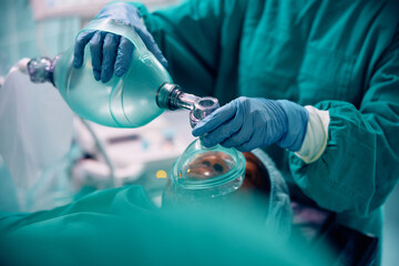 Close up of doctor using oxygen mask patient under anesthesia during surgical procedure.