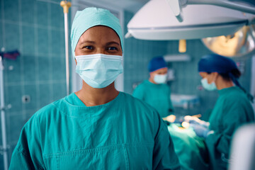Fototapeta na wymiar Happy African American female surgeon in operating room at clinic looking at camera.