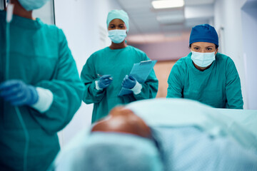 Female surgeon and her team taking patient to recovery room after surgery in hospital.