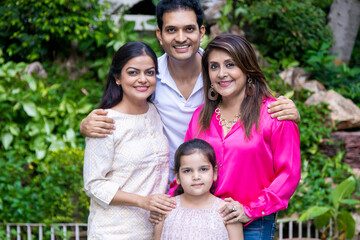 Portrait of happy Indian family standing together. Husband wife cute little daughter and mother.