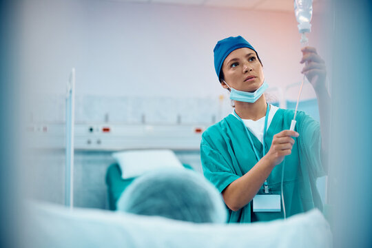 Surgical Nurse Checking IV Drip Of Patient At Hospital Ward.