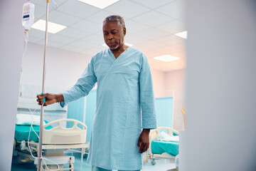 Recovering black senior patient with IV drip at medical clinic.