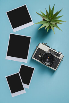 Vintage photo camera and empty photo frames on blue background. Travel moment concept