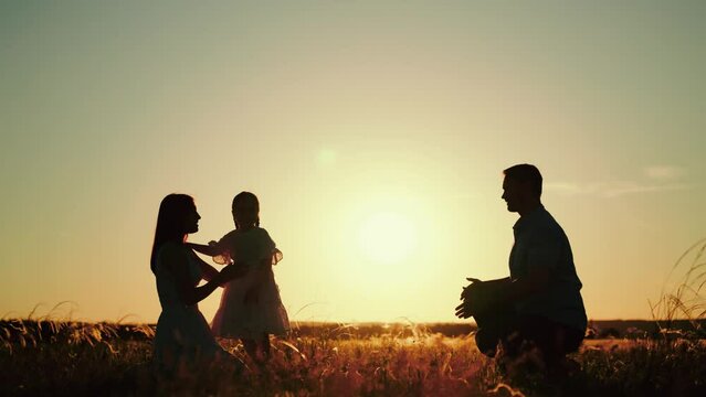 Family plays with daughter running to hugs of parents as sun sets behind rolling field