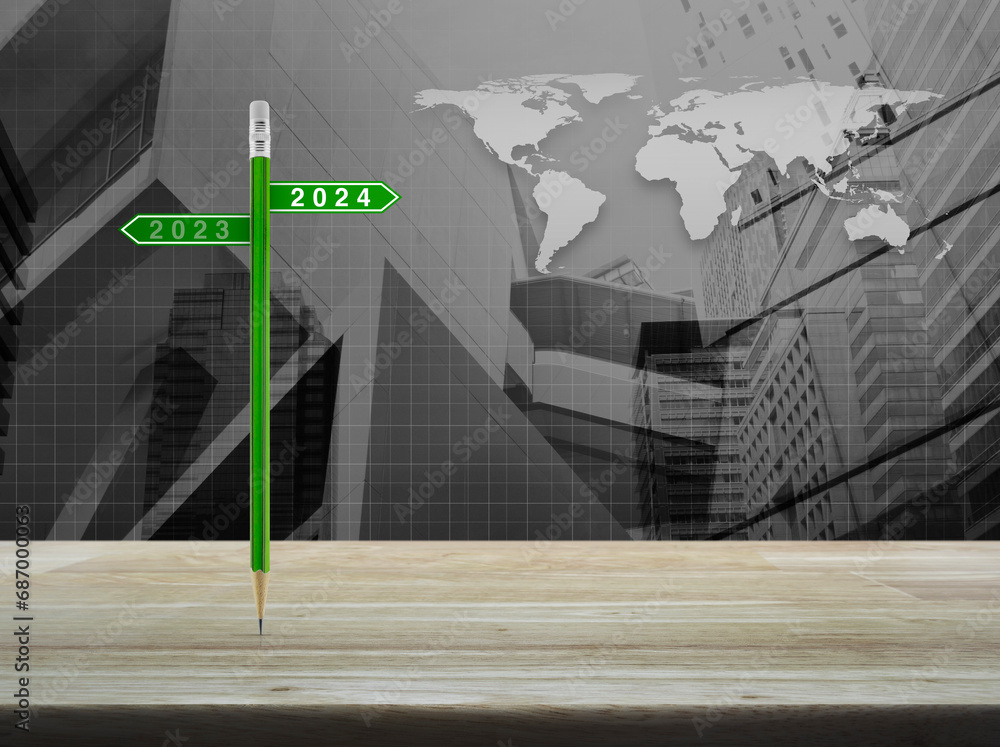 Poster 2024 and 2023 direction sign plate with green pencil on table over world map with financial graph an
