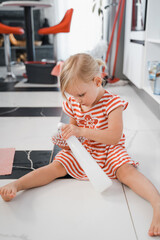 Blonde child girl doing floor washing, using cleaner and brush