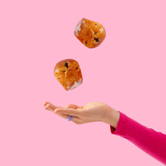 cupcakes levitate on a pink background over a woman's hand