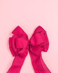 Big Red Christmas Valentine Bow on Pink Background with Copy Space