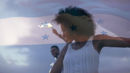 Animation of flag of honduras over happy diverse couple dancing with sparklers on beach at dusk - Powered by Adobe