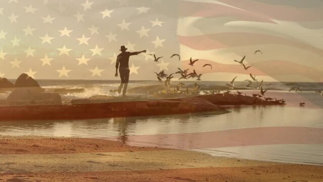 Animation of flag of america over caucasian man in hat running on rocks with birds at sunset beach