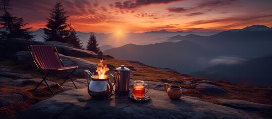 Mountain campsite with tea-filled cups near a blazing fire under the sunset sky.