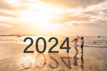 Young couple traveler looking beautiful sunset on the tranquil beach celebrating New Year 2024,...