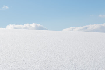 Fototapeta na wymiar Fluffy white clouds and blue sky over winter snow field