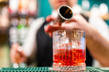 bartender hand making negroni cocktail in bar