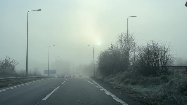 Driving car in winter fog and frost windshield view leaving Manchester's circular M60 motorway, highway at Junction 9, J9.