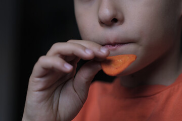 Close-up of a child's hand holding a spicy chip, capturing a quiet moment of simple indulgence and the small joys of childhood snacks.