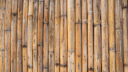 Bamboo cylinders lined up next to each other It's a room wall. Light brown tone It's a natural pattern wall. The surface is not smooth. It has a rounded, undulating shape, varying in size and size. 