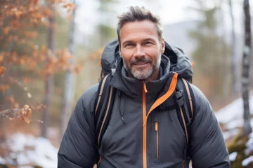 Deurstickers Handsome middle aged man in sportswear smiling at camera while standing outdoors in the forest © igolaizola