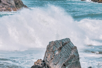Wave splashes close-up. Crystal clear sea water hitting rock formations in the ocean in San...