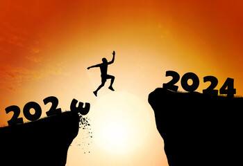 Happy new year 2024. Man silhouette jumping cliff from 2023 to 2024 on cloud sky background.