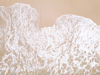 Drone view ocean foam. Transparent clear wave coming on sandy beach aerial shot.