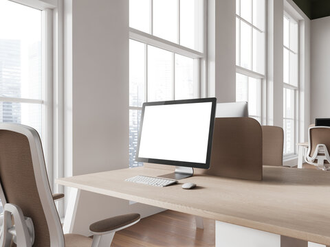 Light coworking interior with pc desktop on table with mockup screen, window