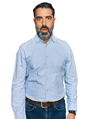 Middle aged man with beard wearing business shirt in shock face, looking skeptical and sarcastic,...