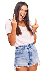 Young hispanic woman wearing casual white tshirt showing middle finger doing fuck you bad expression, provocation and rude attitude. screaming excited