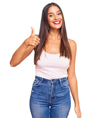 Young hispanic woman wearing casual clothes smiling happy and positive, thumb up doing excellent...