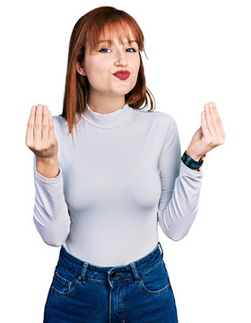 Redhead young woman wearing casual turtleneck sweater doing money gesture with hands, asking for salary payment, millionaire business