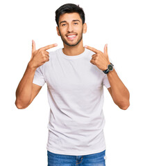 Young handsome man wearing casual white tshirt smiling cheerful showing and pointing with fingers teeth and mouth. dental health concept.