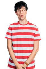 Handsome hipster young man wearing casual striped t shirt making fish face with lips, crazy and comical gesture. funny expression.