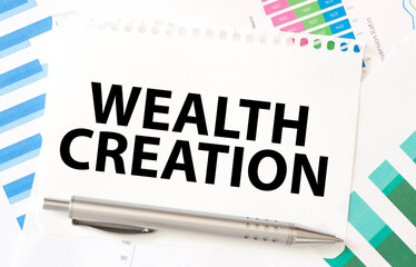 WEALTH CREATION on paper with charts and pen