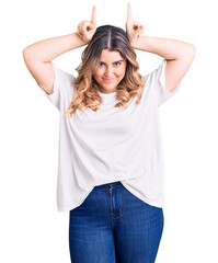 Fototapeta premium Young caucasian woman wearing casual clothes doing funny gesture with finger over head as bull horns