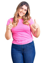 Young caucasian woman wearing sportswear success sign doing positive gesture with hand, thumbs up smiling and happy. cheerful expression and winner gesture.
