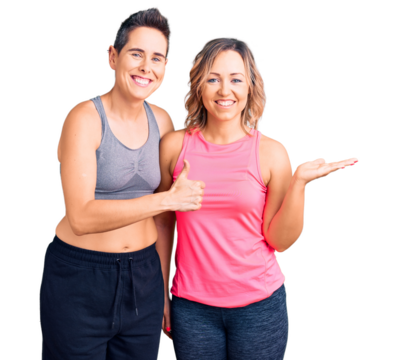Couple of women wearing sportswear showing palm hand and doing ok gesture with thumbs up, smiling happy and cheerful