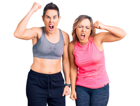 Couple of women wearing sportswear angry and mad raising fist frustrated and furious while shouting with anger. rage and aggressive concept.