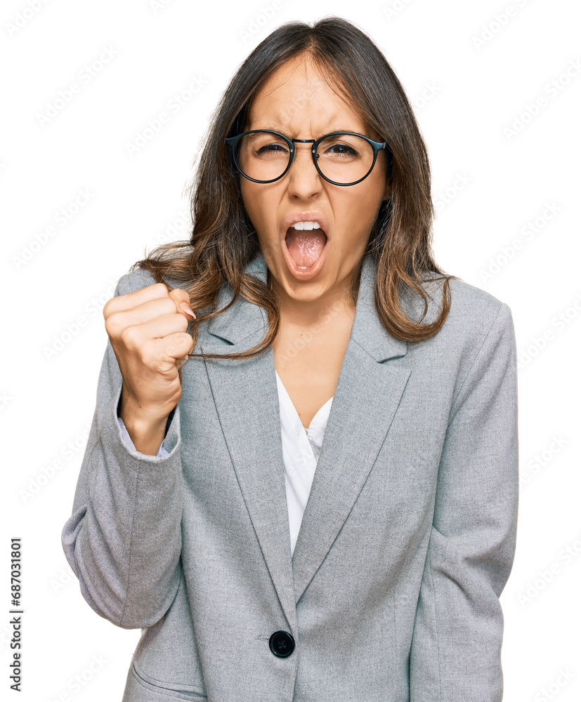 Sticker Young brunette woman wearing business clothes angry and mad raising fist frustrated and furious while shouting with anger. rage and aggressive concept.