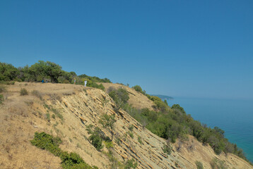 Landscape from a hill cliff with trees and bushes to the blue sea and clear horizon