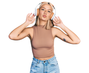 Beautiful young blonde woman listening to music using headphones looking at the camera blowing a kiss being lovely and sexy. love expression.