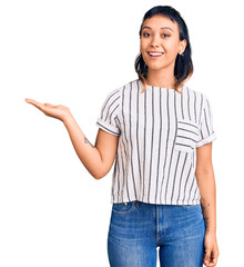 Young woman wearing casual clothes smiling cheerful presenting and pointing with palm of hand looking at the camera.