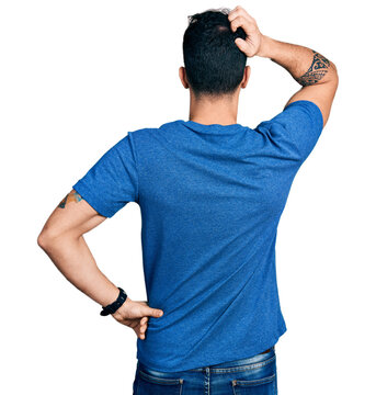 Young hispanic man wearing casual t shirt backwards thinking about doubt with hand on head