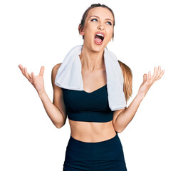 Beautiful caucasian woman wearing sportswear and towel crazy and mad shouting and yelling with aggressive expression and arms raised. frustration concept.