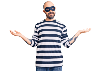 Young handsome man wearing burglar mask smiling showing both hands open palms, presenting and advertising comparison and balance